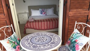 A room with a bed, a round table with chairs, and a nightstand. - Refined detached villa for nature lovers. (Domus De Maria)
