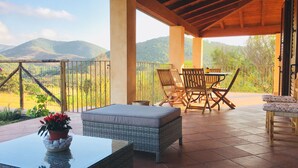 A covered outdoor seating area with a table and chairs, a cushioned bench, and a potted plant. - Refined detached villa for nature lovers. (Domus De Maria)
