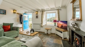 Un salon confortable avec une cheminée, un téléviseur et une vue sur l’extérieur par une fenêtre.
