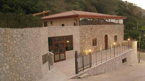 A stone building with a red roof, large windows, and a balcony with lights. - Il Canalotto (Longi)