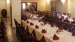 A dining hall with multiple tables set for a meal, each with red napkins and clear glassware. - Il Canalotto (Longi)