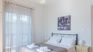 Une chambre d’hôtel avec un lit, une table de chevet, une œuvre d’art murale et une fenêtre ornée de rideaux légers.