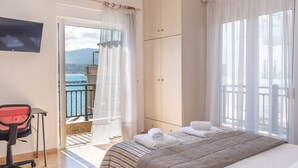 Une chambre d’hôtel avec un lit, un bureau et une télévision. Elle dispose d’un balcon avec vue sur la mer et les montagnes.