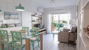 En moderne stue med et glasbord, grønne stole, en sofa og et lille sofabord.