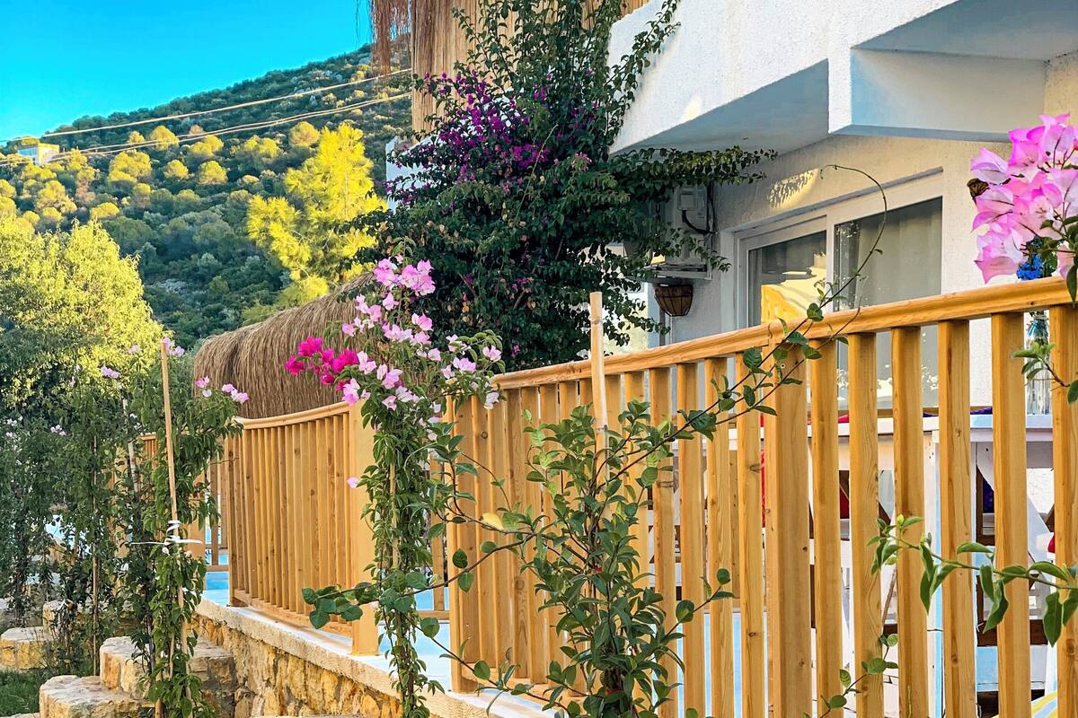 A stone staircase leading to a wooden deck with a thatched roof structure.