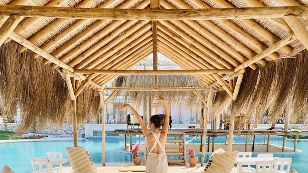 A wooden deck with striped cushions, a pool, and a thatched roof structure. - Alacati Barbarossa Hotel (Cesme)