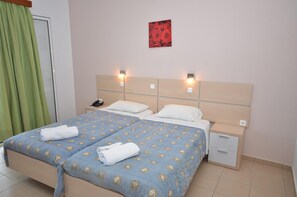 Une chambre d’hôtel avec un lit double, deux tables de chevet, une petite table et un rideau vert.