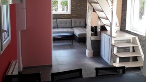 A modern living room with a grey sofa, a small table, and a staircase leading to a loft area.