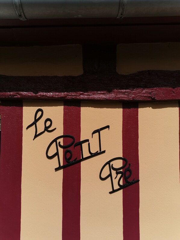 A building facade with vertical red and beige stripes and the text "le Petit" in black letters.