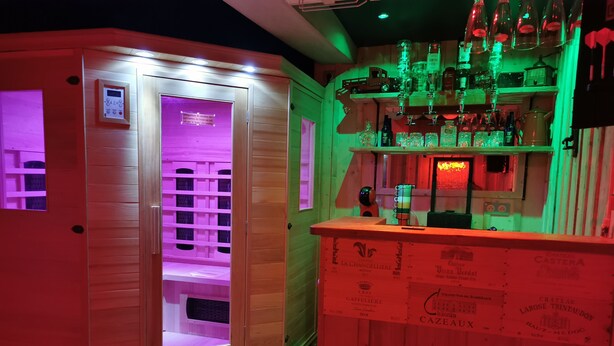A bar area with wooden shelves and a variety of bottles.