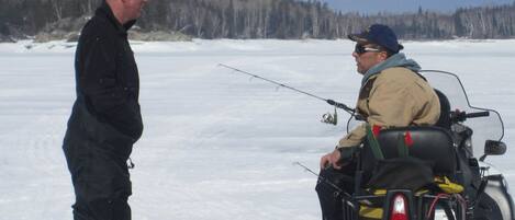 Two people on a snow-covered field, one standing and one on a snowmobile.