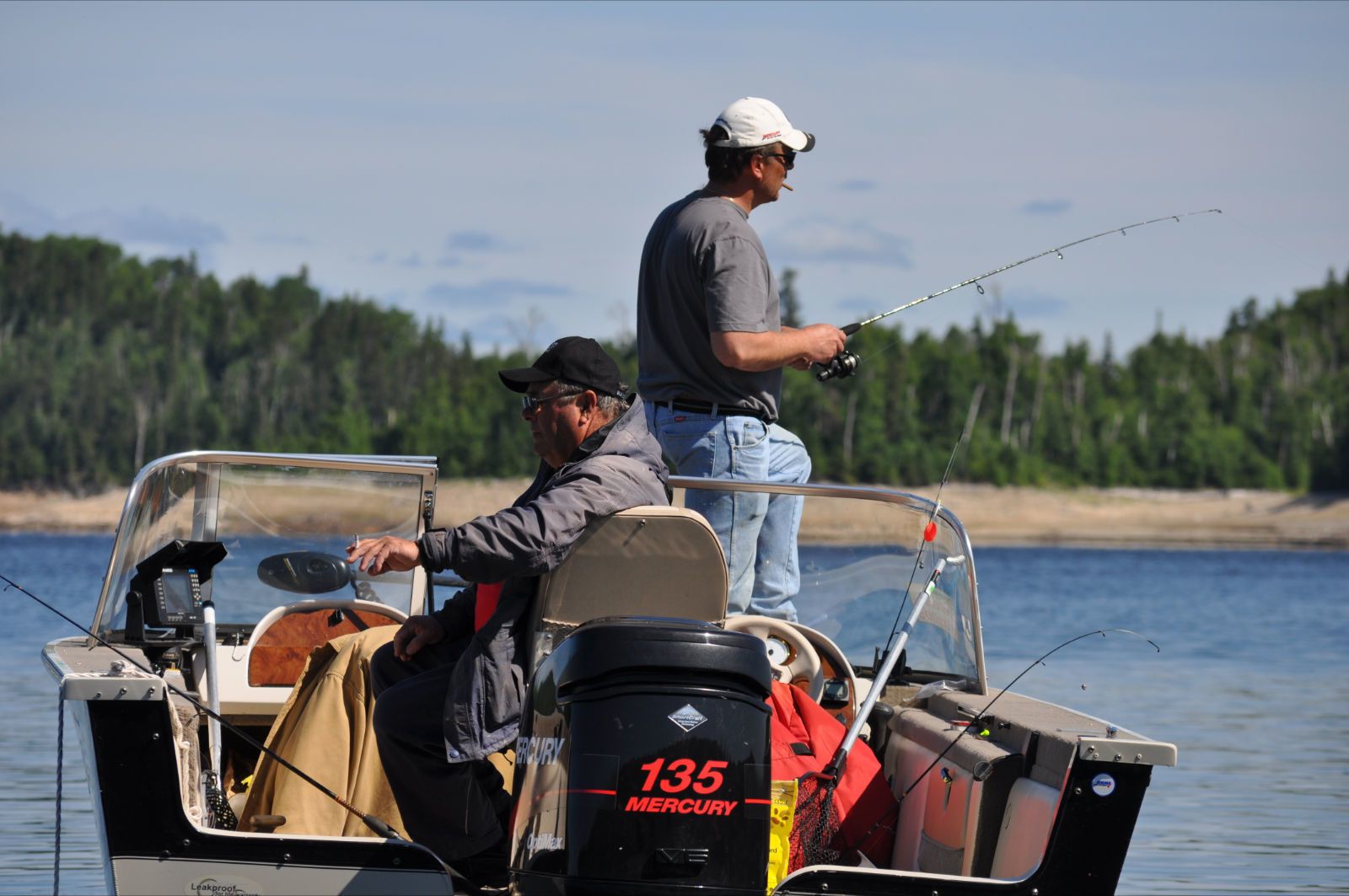 Two people on a small boat with a motor labeled "135 MERCURY".
