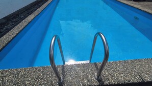 En rektangulær swimmingpool med en klar, blå vandoverflade, omgivet af en kant med småsten.