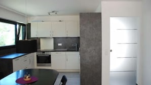 Et moderne køkken med hvide skabe, en sort bordplade og et spiseområde med et bord og stole.