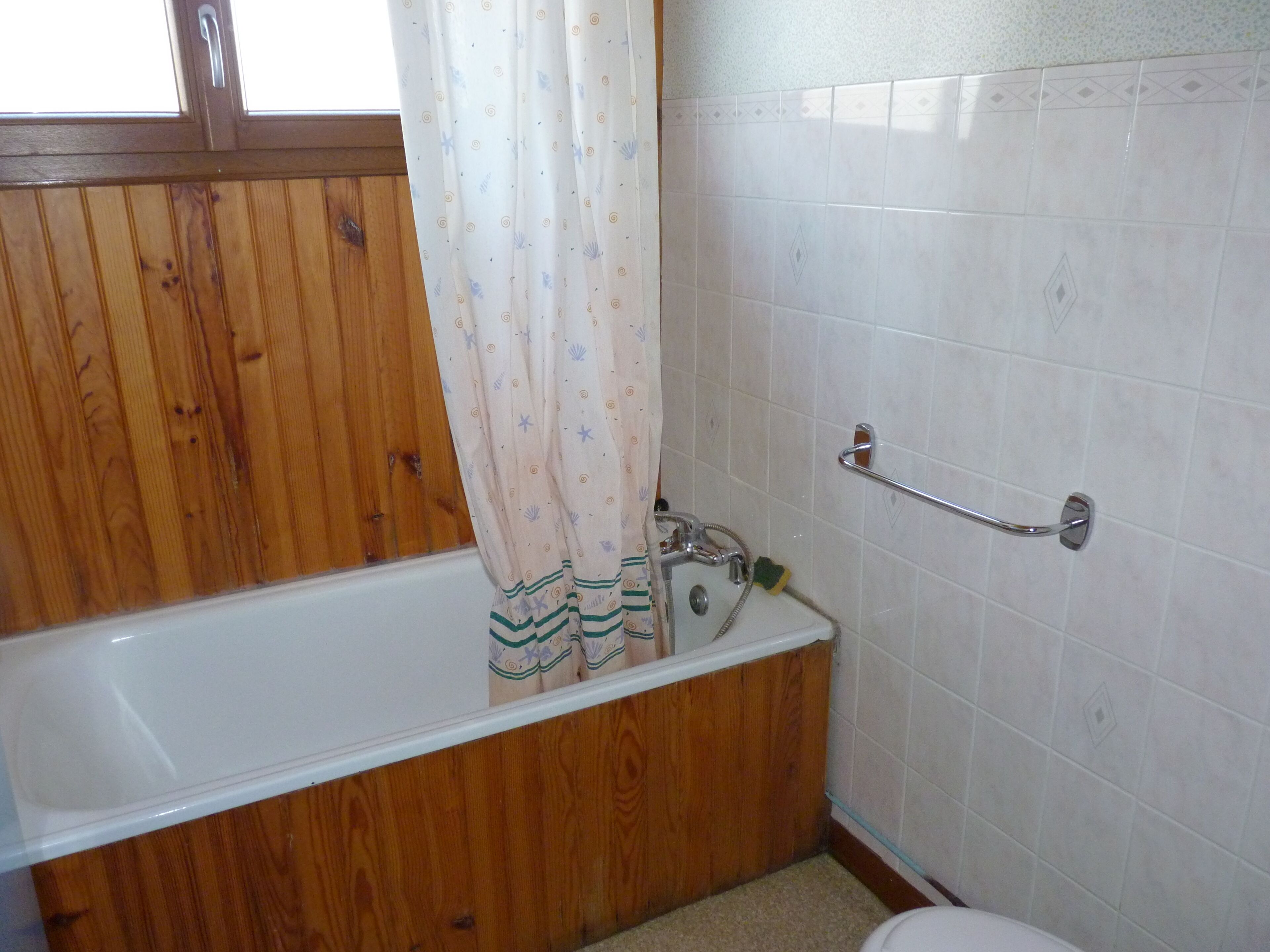 A bathroom with a wooden vanity, a white bathtub, and a shower area.