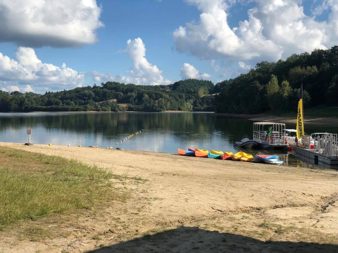 Blick auf ein Seeufer mit Steg, Booten und einem kleinen Bootsanleger.