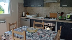 A kitchen with a dining table, chairs, a stove, and cabinets. - APARTMENT IN HOUSE (Lacapelle-Viescamp)