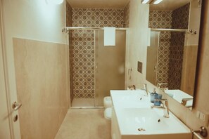 A bathroom with a shower, two sinks, and a large mirror. - La Dimora di Teti (Gallipoli)