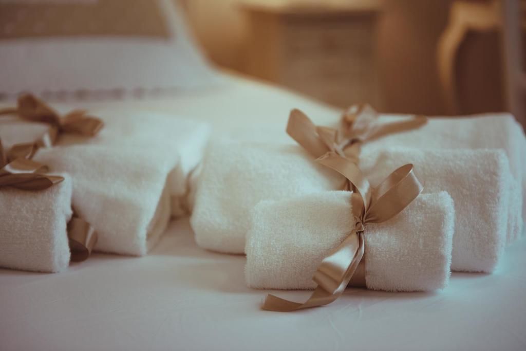 Neatly folded white towels with brown ribbons tied into bows on a bed.