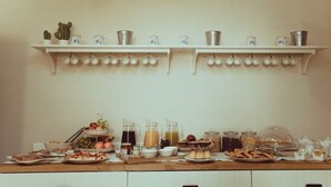A kitchen with two white shelves holding various kitchenware and a breakfast table with food and drinks. - La Dimora di Teti (Gallipoli)