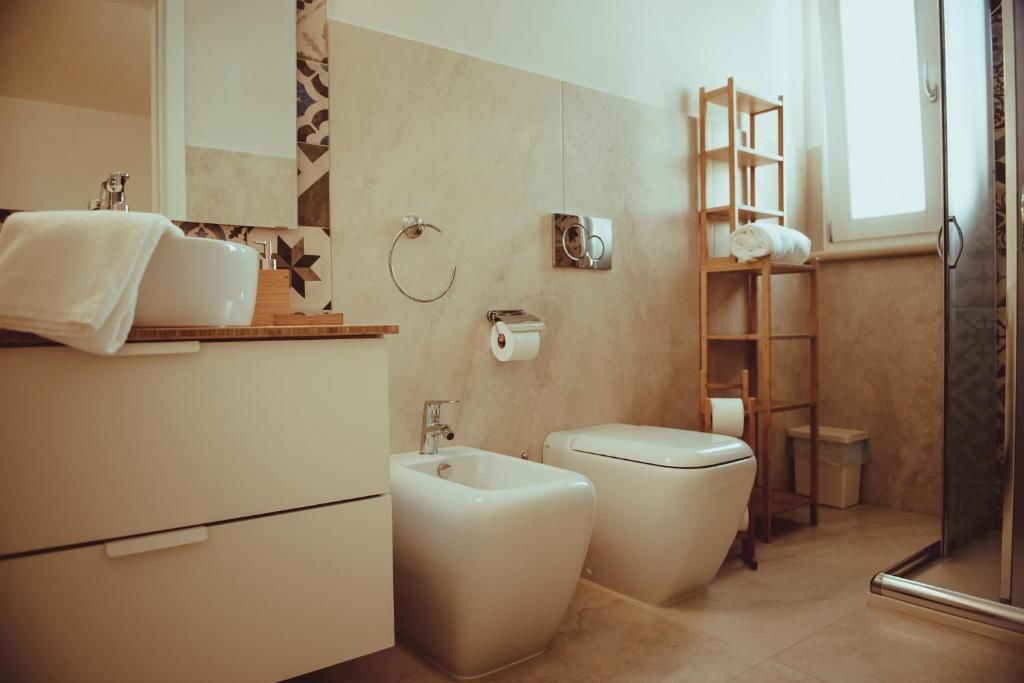 A modern bathroom with a bidet, toilet, and a glass shower enclosure.