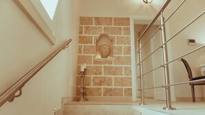 A staircase with a stone wall, a candle holder, and a chair. - La Dimora di Teti (Gallipoli)