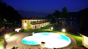 Un área de piscina bien iluminada con una casa al fondo.