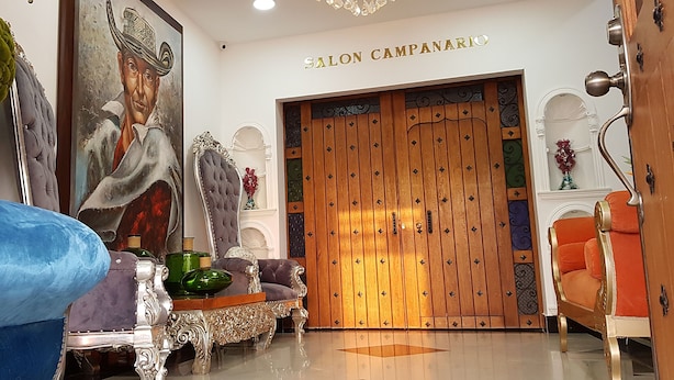 A salon with a wooden door, plush seating, and a chandelier. - Hotel Boutique Campanario del Río (Soledad)