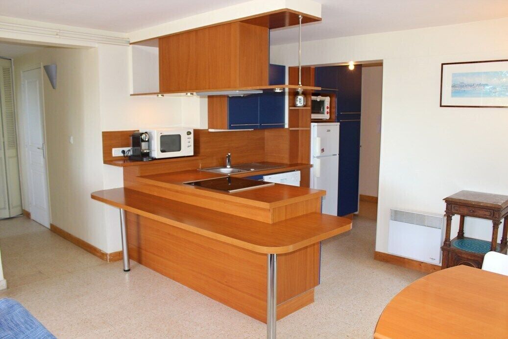 A compact kitchen with wooden cabinets, a built-in microwave, and a small refrigerator.