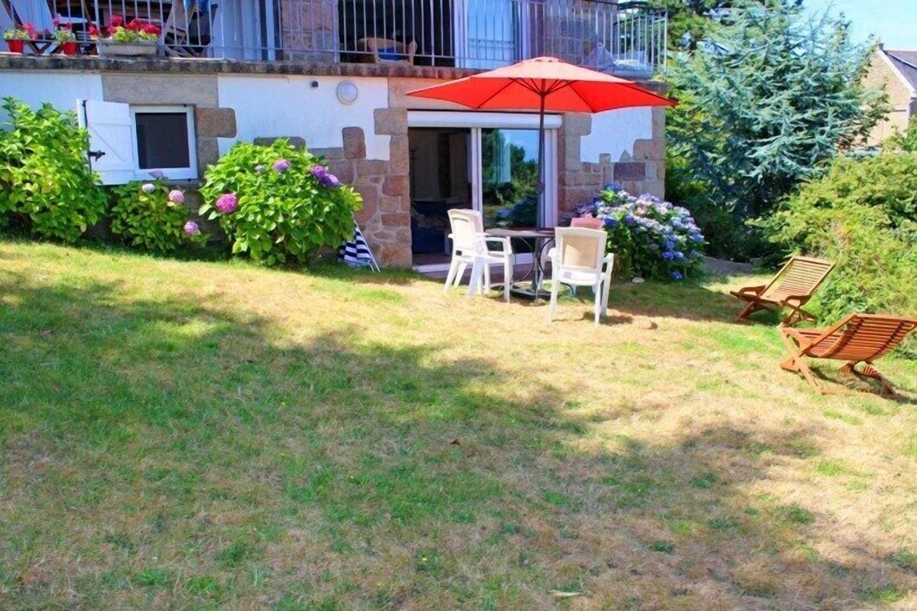 A patio with a table and chairs, a red umbrella, and a wooden chair.