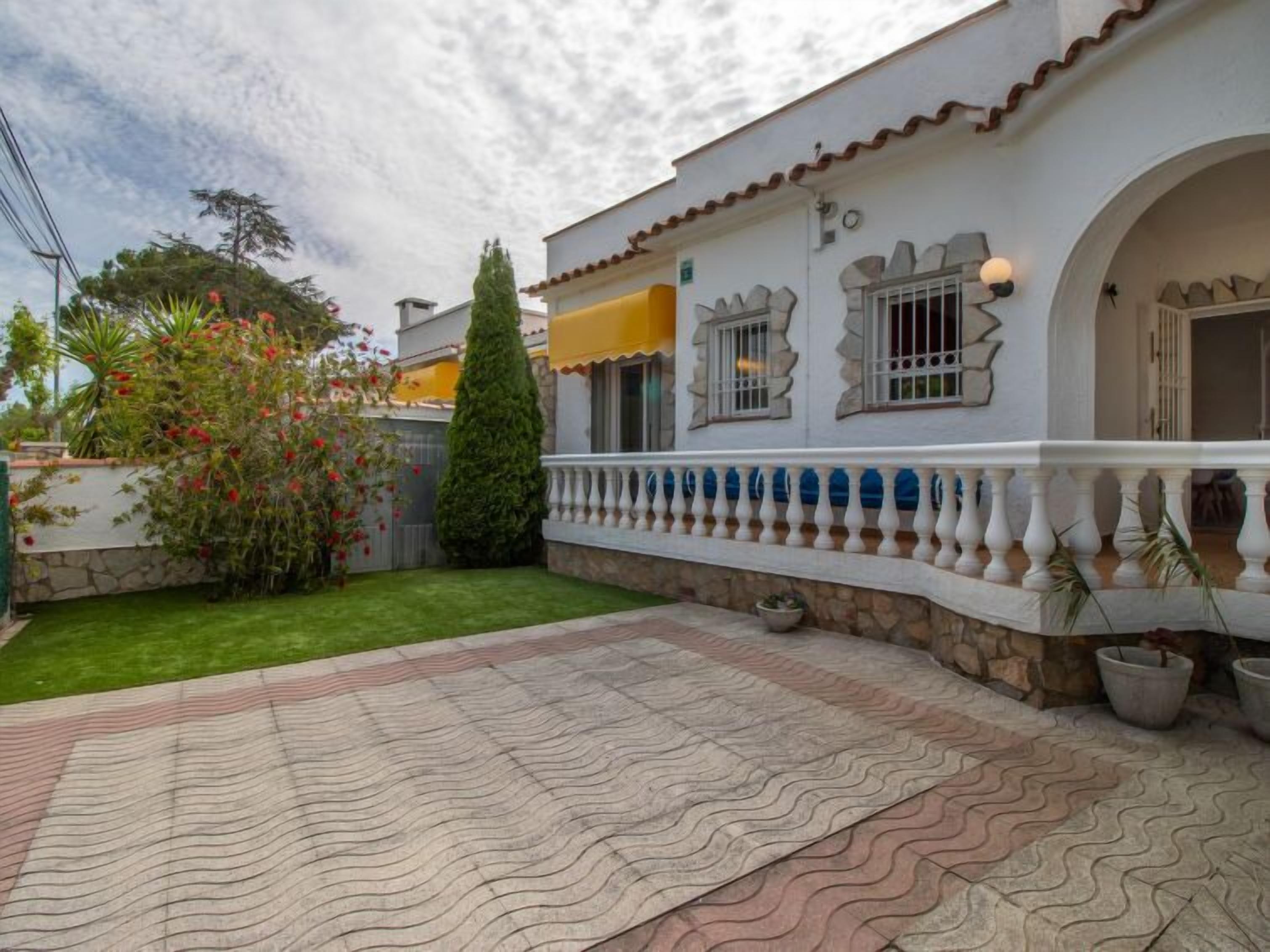 Un immeuble résidentiel doté d’un patio carrelé, d’un petit jardin et d’une clôture blanche.