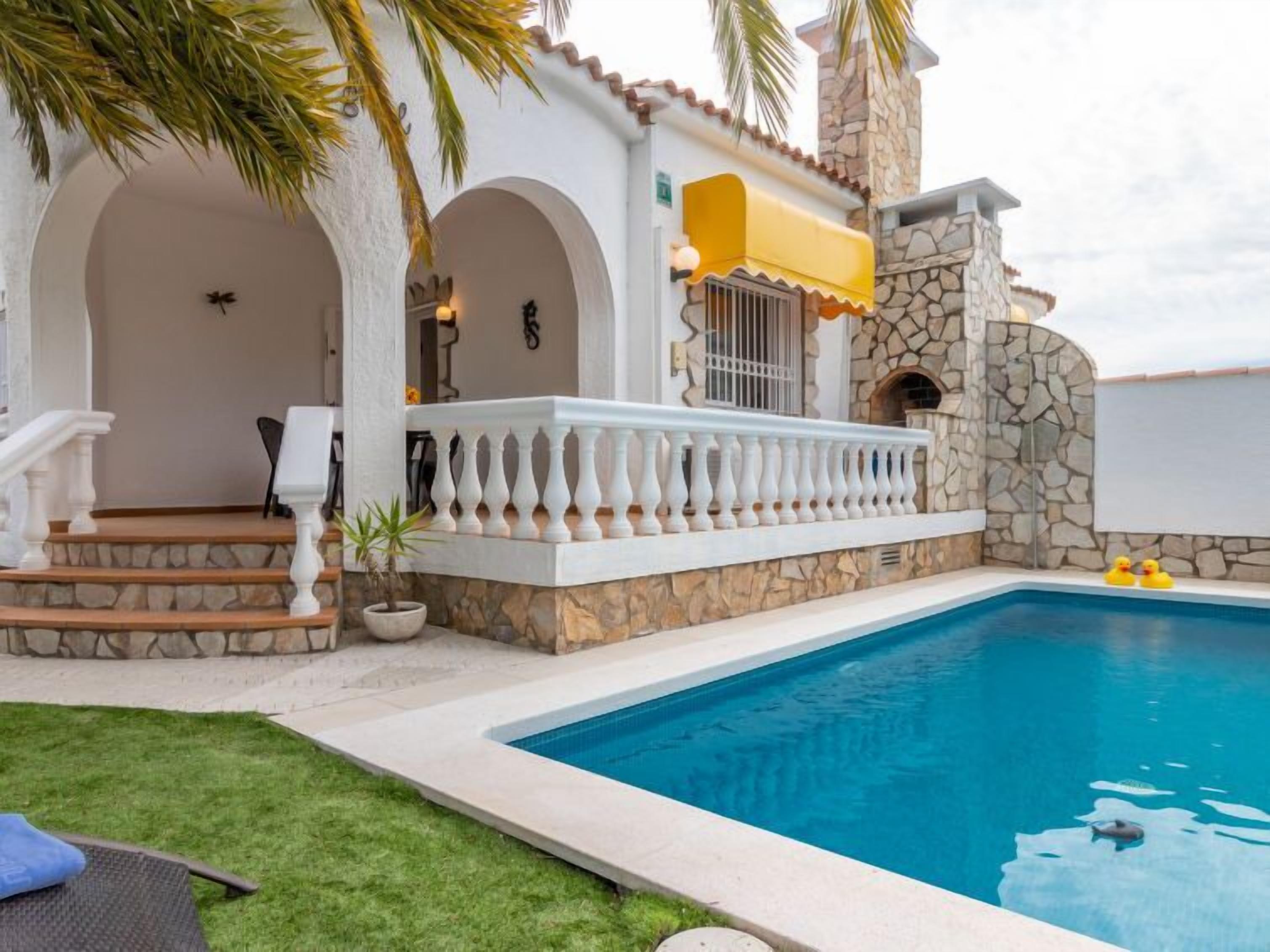 Un'area piscina con un muro in pietra, una zona relax coperta e una piscina cristallina blu.