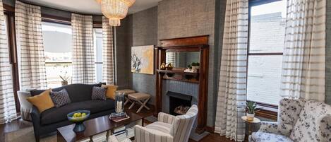 A living room with a dark sofa, striped armchairs, a coffee table, and a fireplace.