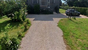 Une maison en pierre avec une allée de gravier menant à une entrée fermée par un portail.