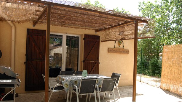 An outdoor patio with a table and chairs, a grill, and a pergola.