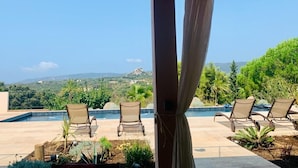 Un área junto a la piscina con sillones reclinables, una pérgola y vistas a un paisaje montañoso.