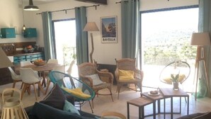 Una sala de estar con sofá, sillas, una mesa de comedor y vistas al exterior.