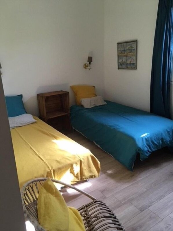 A small, simple room with two single beds, a wooden nightstand, a small table, and a chair. - Big house charm view beaches 5 minutes (Pianottoli-Caldarello)