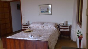 A bedroom with a wooden bed, a hat, and a framed picture on the wall.