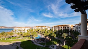 Un resort con varias construcciones, piscina, palmeras y playa.