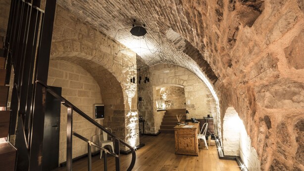 Interior con paredes de piedra, una escalera de madera, un escritorio y una silla.