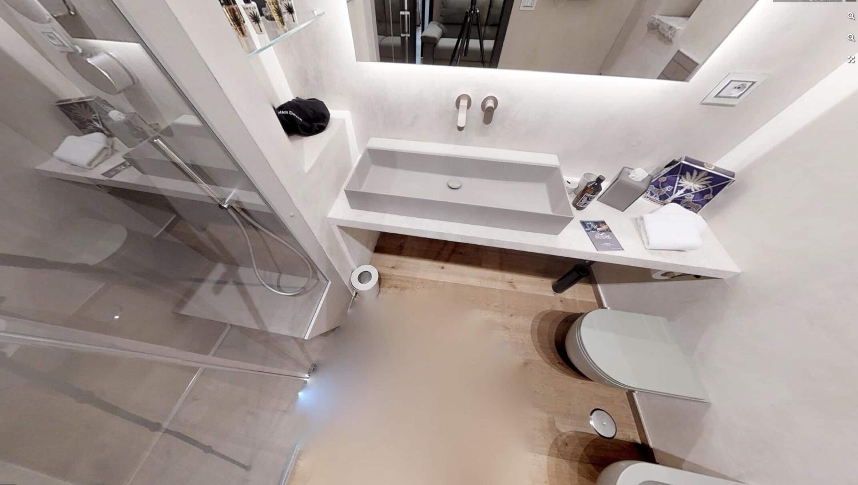 A modern bathroom with a glass shower enclosure, a white sink, and a toilet.