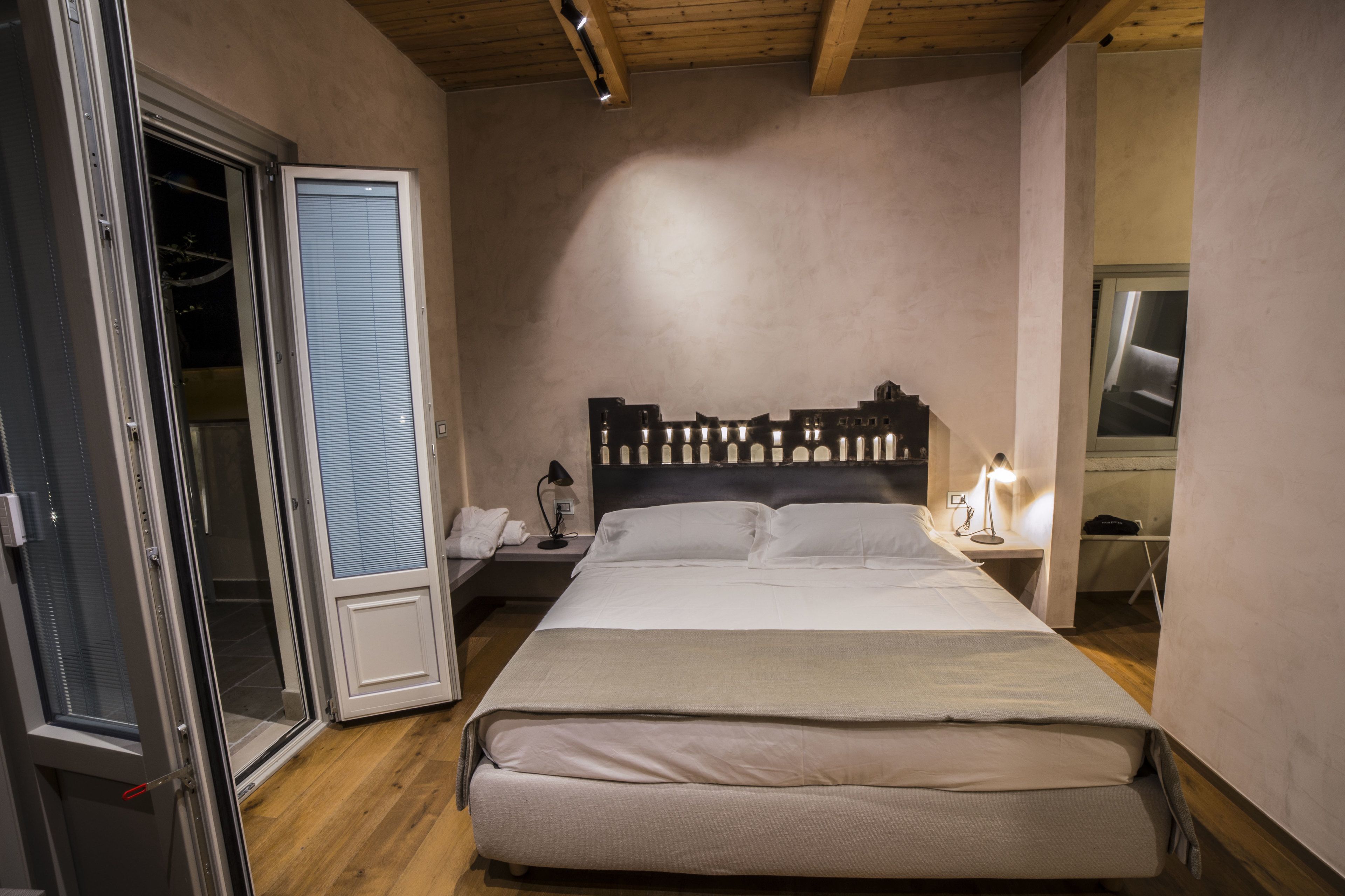 A bedroom with a large bed, a nightstand, a lamp, and a sliding door.
