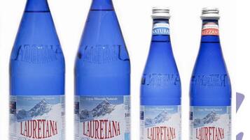 Four bottles of Lauretana water, two labeled as natural and two as frizzante, with a mountain landscape on the label.