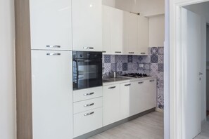 A modern kitchen with white cabinets, a black oven, and a tiled backsplash.