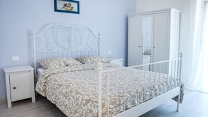 A bedroom with a white metal bed frame, a white nightstand, a wardrobe, and a framed picture on the wall. - S051 - Sirolo, new three-room apartment with garden (Sirolo)