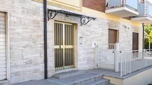 A building with a stone facade, a metal gate, and a white railing. - S051 - Sirolo, new three-room apartment with garden (Sirolo)