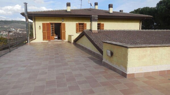 A residential building with a tiled patio, a chimney, and a satellite dish.
