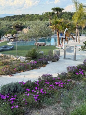 A landscaped area with a pool, palm trees, and purple flowers. - Villa le Cyprès for 4 pers (Montagnac)