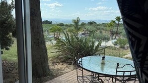 Une terrasse avec une table ronde et des chaises, offrant une vue sur un paysage arboré et un horizon lointain.